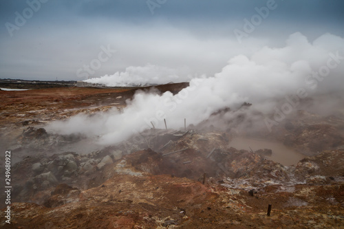 Desolate landscape of Iceland volcanic brown soil with steamy geyser mist