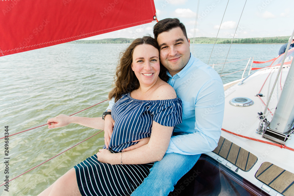 Cheerful pregnant woman with husband on yacht. Happy pregnancy concept. Young family on vacation. Candid photo.