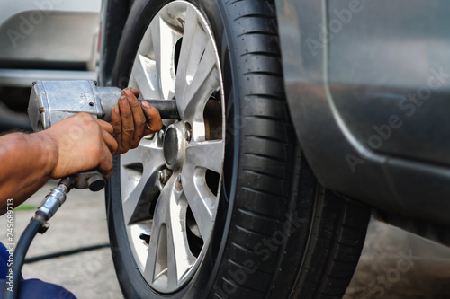 Tire Replacement concept. Mechanic Using Electric Screwdriver Wrench for Wheel Nuts in Garage. Car Maintenance and services