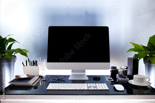 Workplace with modern desktop computer on glass table, Mock up black screen, Houseplant and supplies.