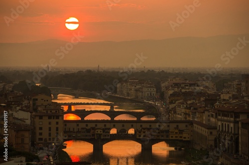 View of the River Arno and famous bridge Ponte Vecchio. Amazing evening golden hour light. Beautiful gold sunset in Florence, Italy.
