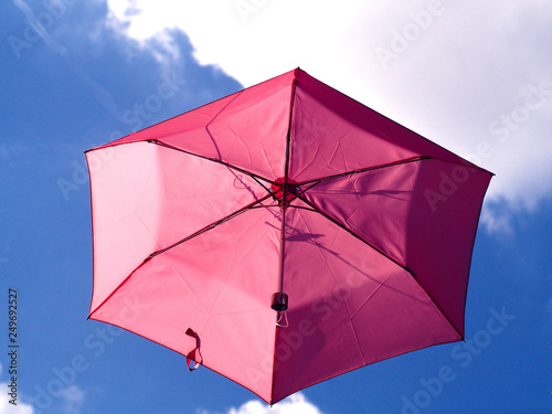 Pink umbrella is on the air with blue sky background photo