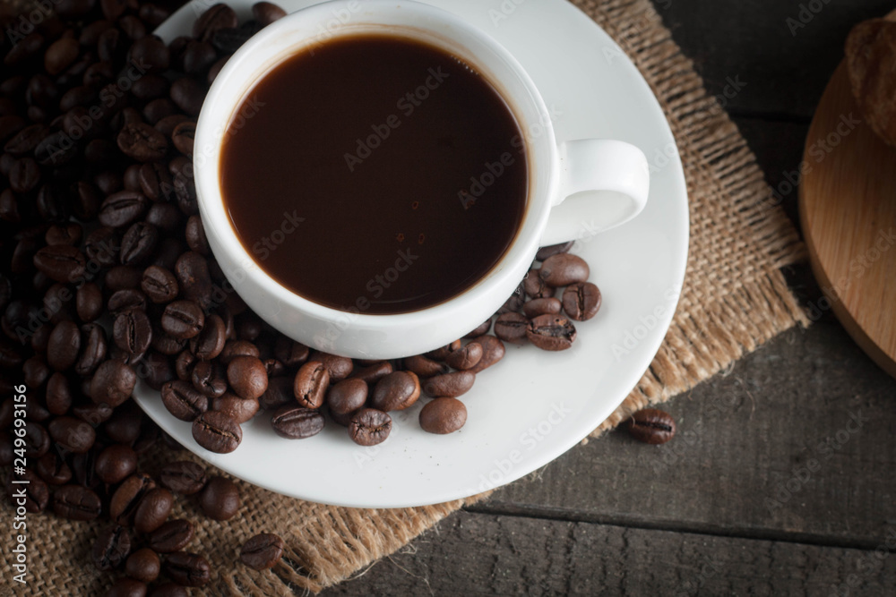Coffee cup and beans on a rustic background. Coffee Espresso and a piece of cake with a curl. Cup of Coffee and coffee beans on table. Coffee cup and beans on a rustic background. Coffee Espresso and a piece of cake with a curl. Cup of Coffee and coffee beans on table.