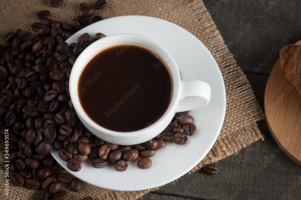Coffee cup and beans on a rustic background. Coffee Espresso and a piece of cake with a curl. Cup of Coffee and coffee beans on table. Coffee cup and beans on a rustic background. Coffee Espresso and a piece of cake with a curl. Cup of Coffee and coffee beans on table.