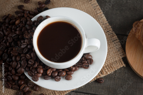 Coffee cup and beans on a rustic background. Coffee Espresso and a piece of cake with a curl. Cup of Coffee and coffee beans on table.