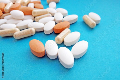 Pharmacy theme, health care, drug prescription for treatment medication and pharmaceutical medicament. Assorted colorful pharmaceutical medicine pills, tablets and capsules on blue background.