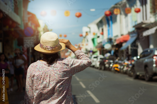 Woman traveler in casual dress walking in thalang road with chino portuguese style building.