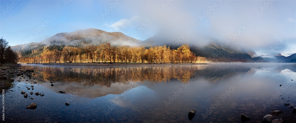 Fototapeta premium Scottish Loch in the early morning. A very calm autumn day at Loch Voil, near Balquhidder in the Loch Lomond and Trossachs National Park, Scotland. Beautiful landscape reflection in water.
