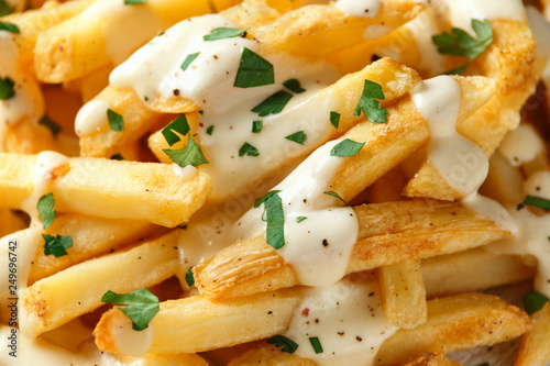 Homemade Baked Potato Fries with cheese sauce on white wooden board. closeup