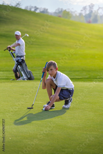 Boy playing golf, makigng shot on the green