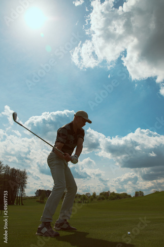 Man playing golf and hitting a golf ball at sunny day