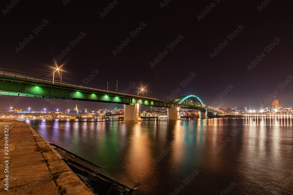 Belgrade, Serbia - February 10, 2019: Belgrade waterfront  and Old bridge on the Sava River. Panorama of Belgrade by night with reflection. 
