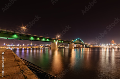 Belgrade, Serbia - February 10, 2019: Belgrade waterfront and Old bridge on the Sava River. Panorama of Belgrade by night with reflection. 
