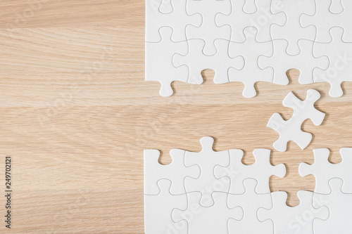Puzzle jigsaw game piece on light cream brown wood texture background