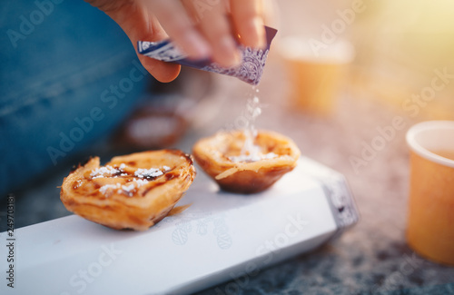 Portuguese Cake - Pasteis de Belem or Nata. Pasteis de Belem with Sugar Powder and Cinnamon. Sunrise in the Background