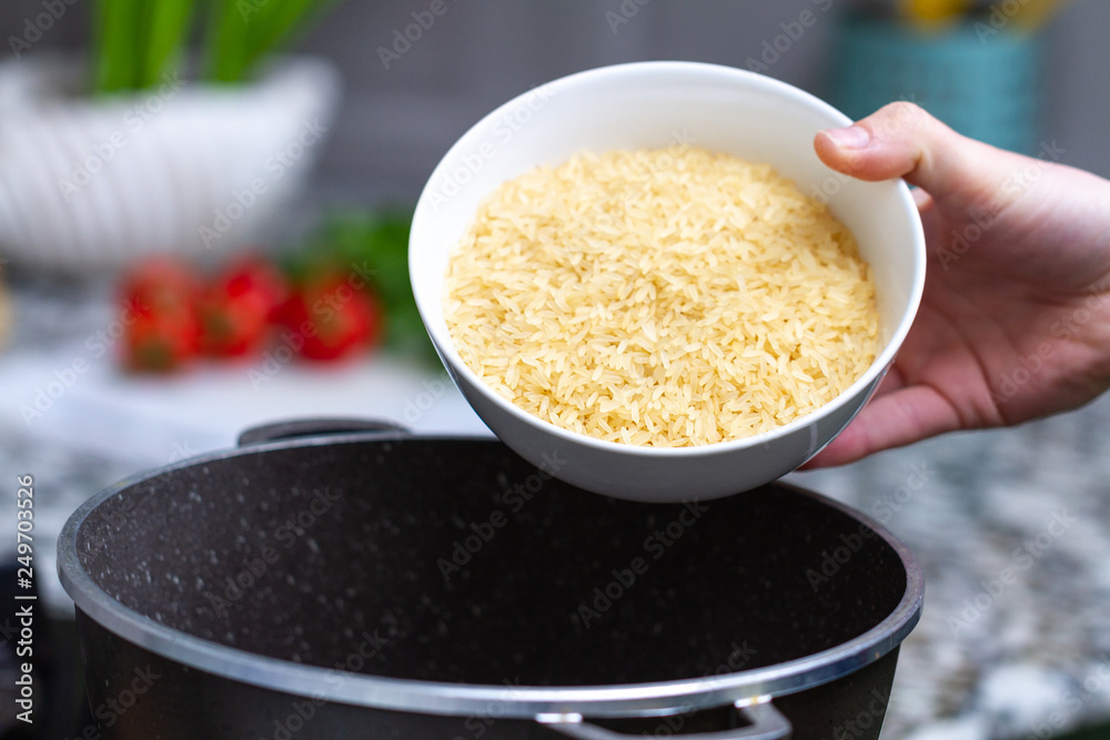 Cooking dry golden yellow long rice in a saucepan for delicious meals from groats with vegetables at home Cooking dry golden yellow long rice in a saucepan for delicious meals from groats with vegetables at home