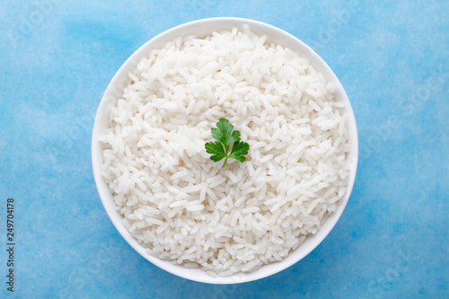 Fotografi Bowl with white boiled rice with green fresh parsley for delicious healthy lunch on a blue background