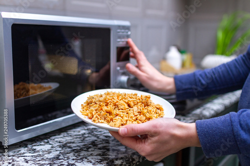 Using a microwave to warming a plate of homemade pilaf for lunch at home. Hot meal photo