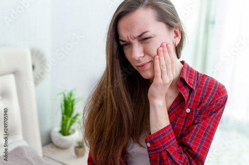 Young woman suffering and experiencing strong aching toothache. Tooth decay and sensitivity. Diseases gums