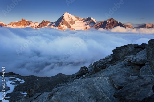 View of snow covered landscape with Weisshorn mountain in the Swiss Alps near Zermatt. Panorama of the Weisshorn and surrounding mountains in Switzerland above the clouds Beautiful morning background