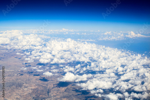 flight above the clouds. The shadows of the clouds on earth. Blue horizon