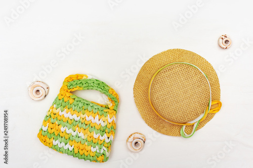Beach accessories on white background. Sun hat and knitted bag. Summer holidays. Copy space.