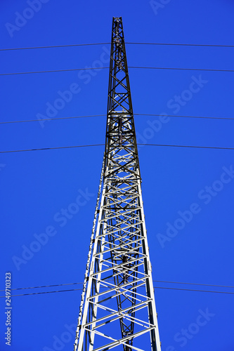 Perspective view of a high voltage transmission tower against blue sky background. Electricity pylon in Germany.