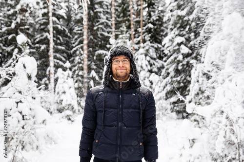 Man in fur winter hat with ear flaps smiling portrait. Extreme in the forest