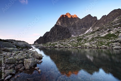Spring or summer morning by lake in mountains. Morning beautiful nature scene. High Tatras mountain lake at reflection in water, Carpathians, Slovakia. Beautiful morning background