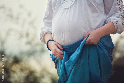 pregnancy, clothes of a pregnant woman, woman holding belly, walking in nature