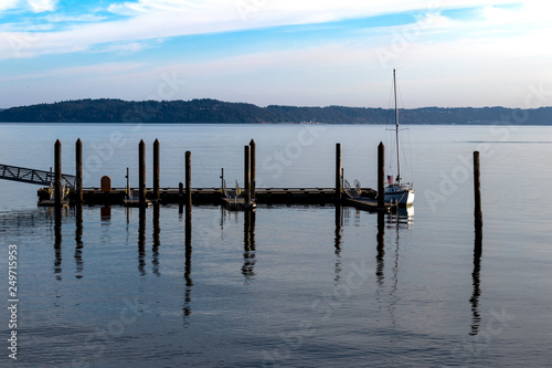 Sailboat docked at a pier with blue cloudy sky