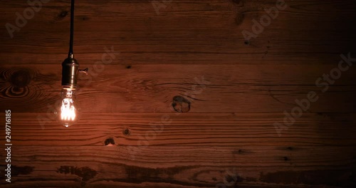 an old vintage light bulb hanging against a grunge wooden wall background