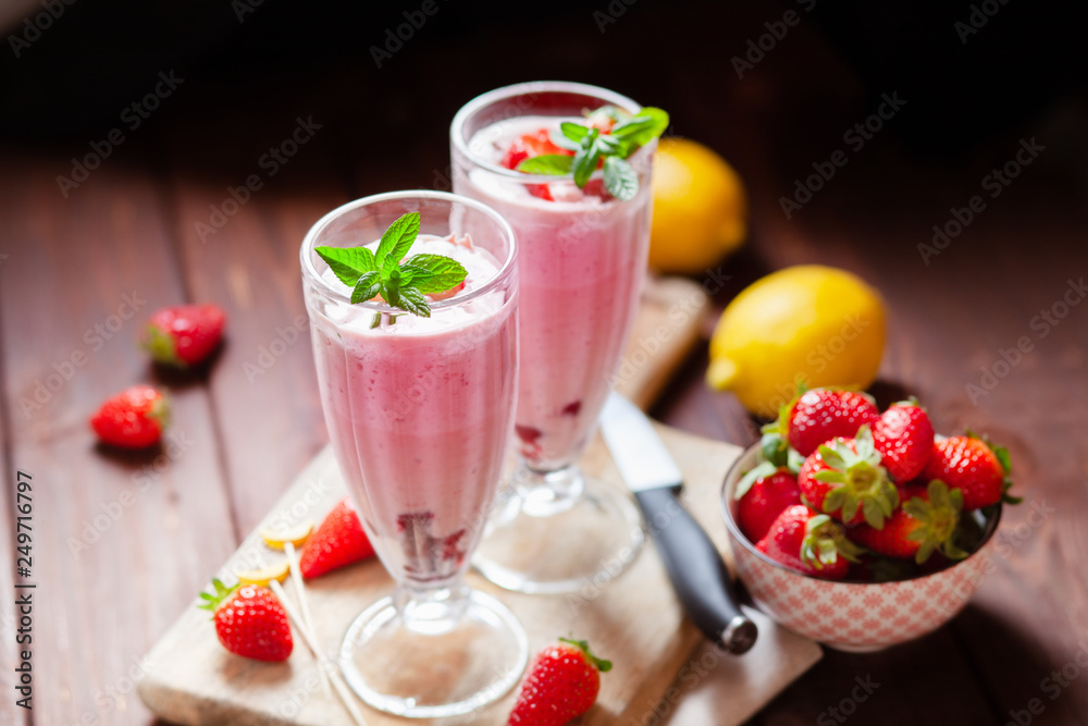 Refreshing milkshakes and bowl with fresh strawberry on wooden table Refreshing milkshakes and bowl with fresh strawberry on wooden table