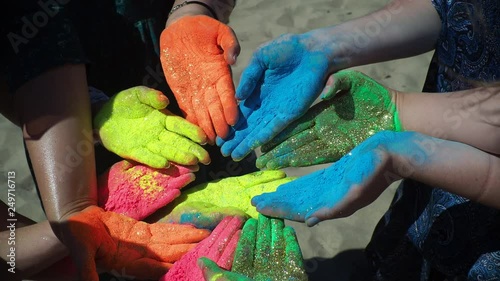 The festival of colors Holi. Hands painted in mixed colors close up. Male and female persons sitting on beachline and doing hindian ritual. Scereny colorful picture of peace and art, summer enjoyment photo