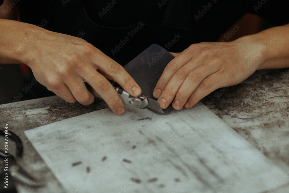 Close up of leather craftsman working with natural leather and tools. Handmade master at work in local workshop. Leather wallet stitch. Close up of leather craftsman working with natural leather and tools. Handmade master at work in local workshop. Leather wallet stitch.