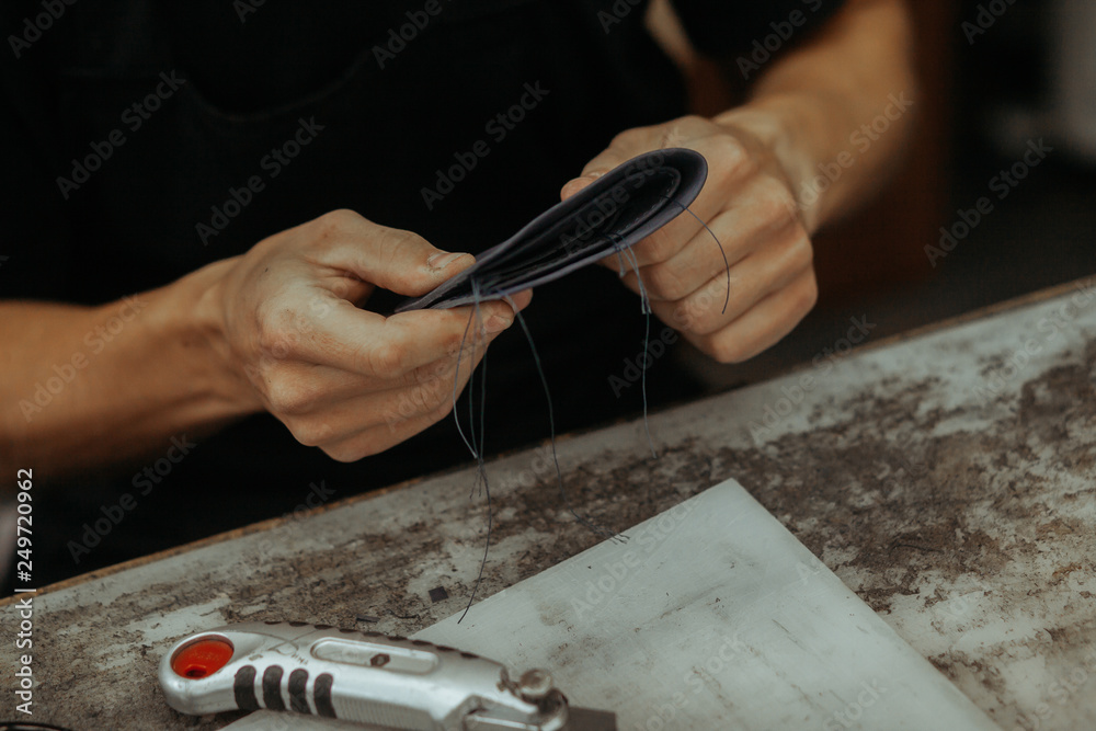 Close up of leather craftsman working with natural leather and tools. Handmade master at work in local workshop. Leather wallet stitch. Close up of leather craftsman working with natural leather and tools. Handmade master at work in local workshop. Leather wallet stitch.