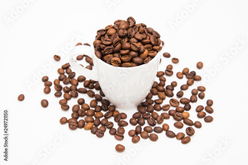 White cup filled with coffee beans with scattered coffee beans on a white background