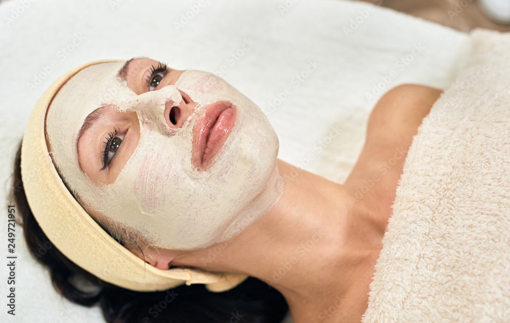 Naklejka premium Portrait of attractive young woman lying in beauty salon with mask on her face