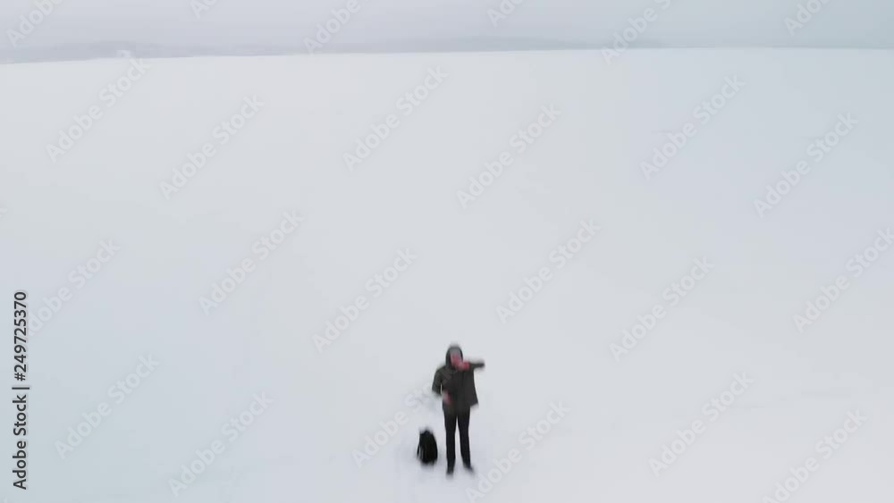 Man waving to the flying drone on the frozen lake Man waving to the flying drone on the frozen lake