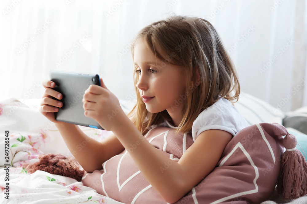 Preteen school girl of 8-9 years old playing on tablet pc at home Preteen school girl of 8-9 years old playing on tablet pc at home