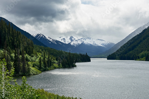 View at Duffey Lake, with overcast sky above snow covered mountains, surrounded by forest, along Highway 99, near Whistler, British Columbia, Canada