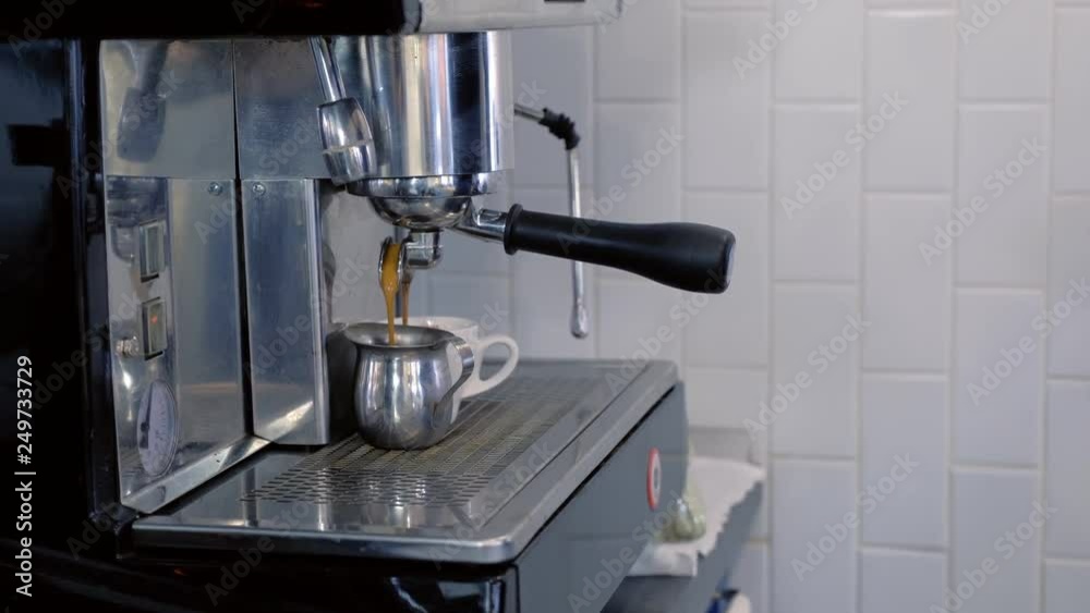 Barista pours espresso to pitcher from coffee machine. Hands close-up. Barista pours espresso to pitcher from coffee machine. Hands close-up.