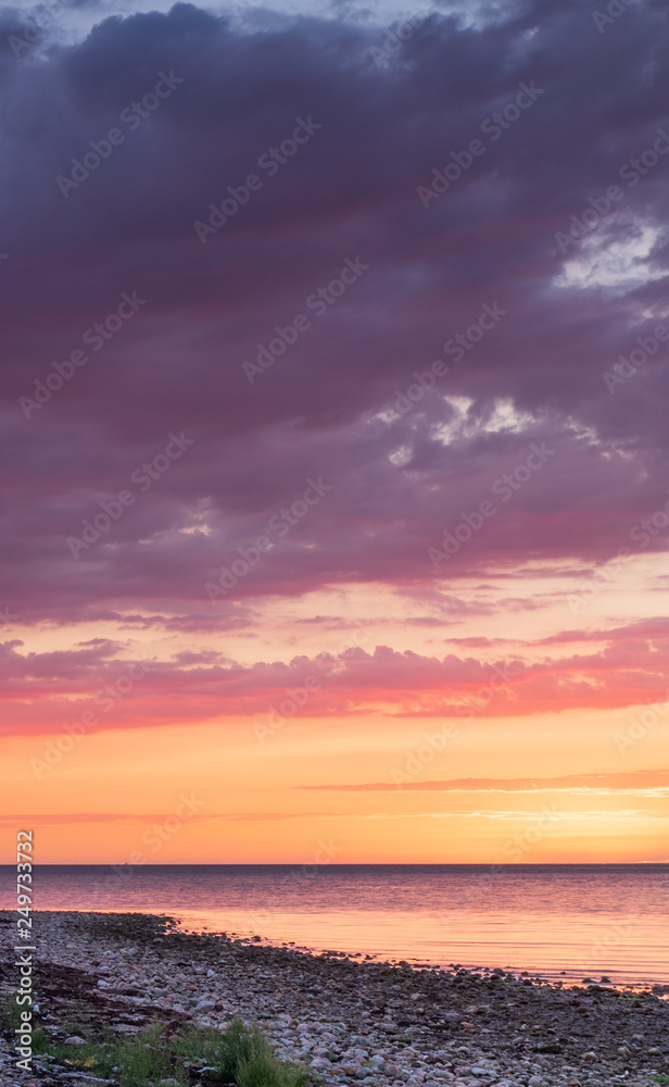 Sunset over a stone beach with a dramatic colors and clouds. Hittarps revet is an unknown beauty in Helsingborg, Sweden. 