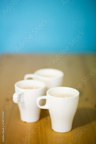 background with three white coffee cups, milk drink, top view
