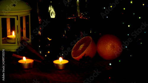 Fototapeta Naklejka Na Ścianę i Meble -  Christmas lights flicker at the holiday table. The candle burns and is reflected in glasses with mulled wine.