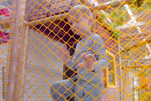 Kid playing at new playground kindergarten behind the net.
