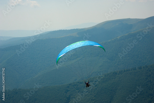 Paraglider fly over a mountain valley on a sunny summer day. Paragliding in the Carpathians in the summer.