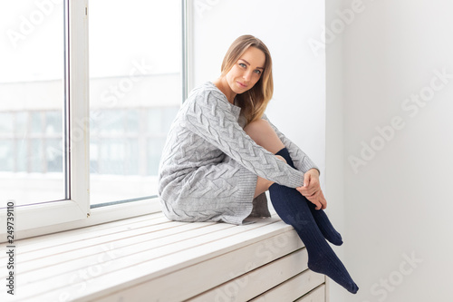 People and fashion concept - Gorgeous romantic woman in wool dress sitting on the window sill
