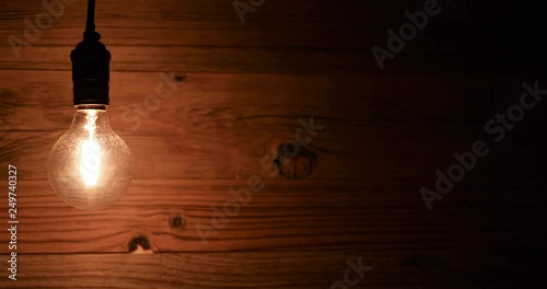 an old vintage light bulb flickering against a grunge wooden wall background