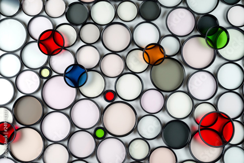 Multicolored round glass photographic filters of various sizes on a light background.